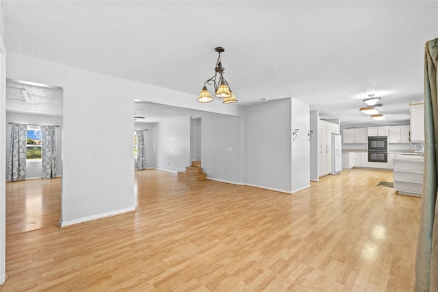 unfurnished living room featuring a textured ceiling, light hardwood / wood-style floors, and a notable chandelier