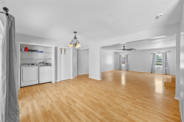 unfurnished living room with ceiling fan with notable chandelier, a textured ceiling, light wood-type flooring, and washer and clothes dryer