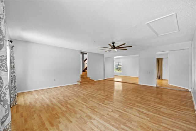 unfurnished living room featuring ceiling fan, light wood-type flooring, and a textured ceiling