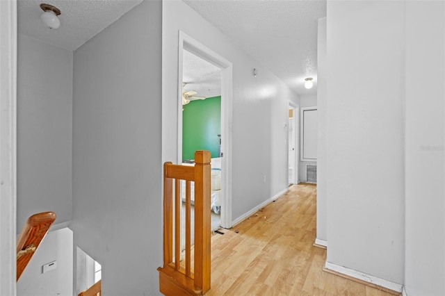 corridor featuring a textured ceiling and light hardwood / wood-style floors