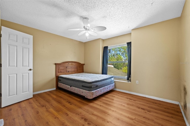 bedroom with hardwood / wood-style flooring, ceiling fan, and a textured ceiling