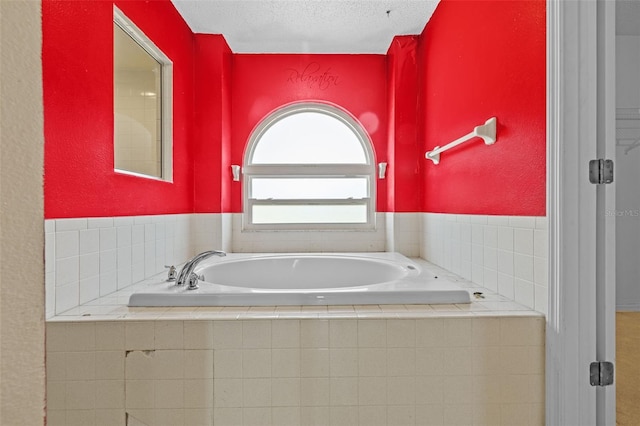 bathroom with a textured ceiling and tiled bath