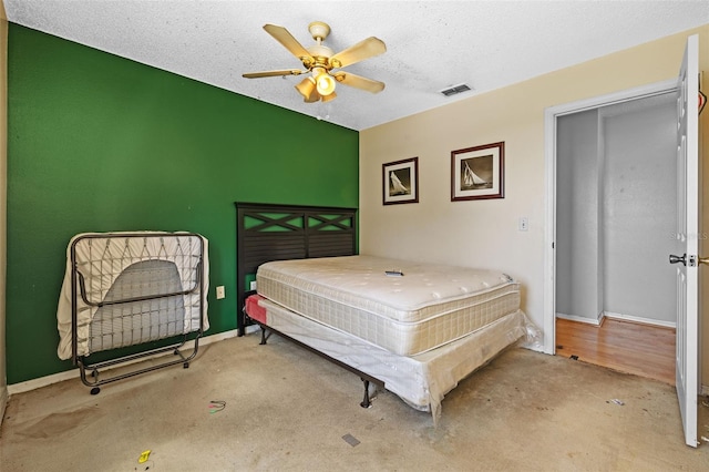 bedroom featuring ceiling fan, light colored carpet, and a textured ceiling