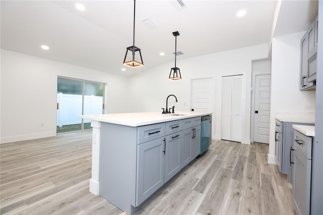 kitchen featuring sink, gray cabinetry, hanging light fixtures, a center island with sink, and stainless steel dishwasher