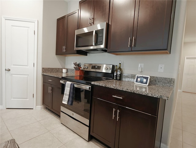 kitchen featuring stone counters, dark brown cabinetry, stainless steel appliances, and light tile patterned flooring