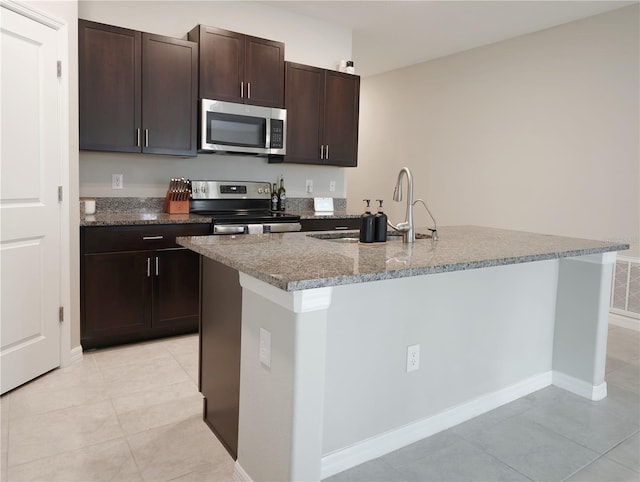 kitchen featuring appliances with stainless steel finishes, dark brown cabinetry, a kitchen island with sink, and sink