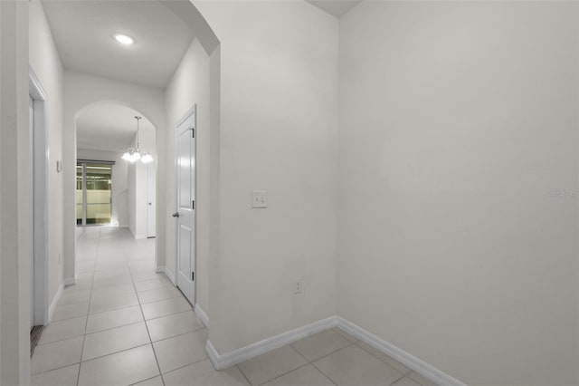 corridor with light tile patterned floors and an inviting chandelier