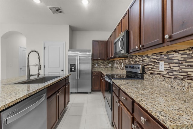 kitchen featuring light stone countertops, sink, tasteful backsplash, light tile patterned flooring, and appliances with stainless steel finishes