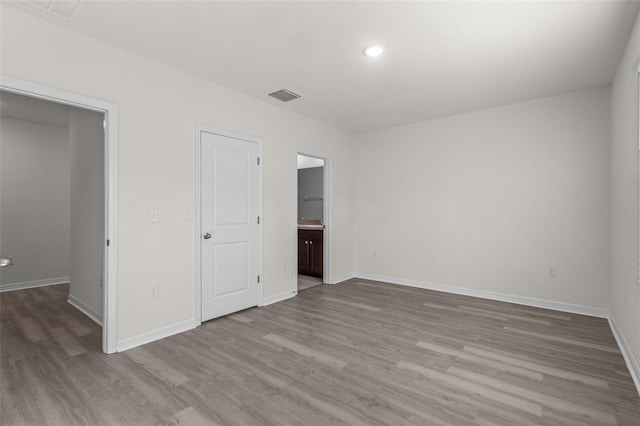 unfurnished bedroom with connected bathroom and light hardwood / wood-style floors