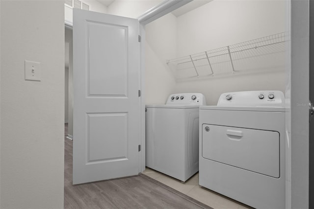 clothes washing area with independent washer and dryer and light wood-type flooring