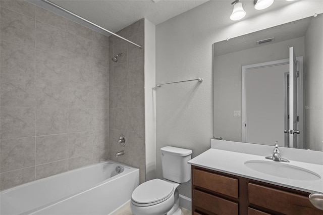 full bathroom with a textured ceiling, vanity, toilet, and tiled shower / bath