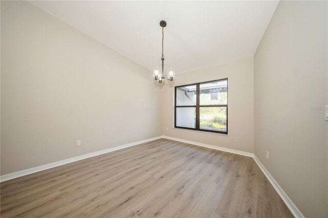 unfurnished room with a chandelier and light wood-type flooring