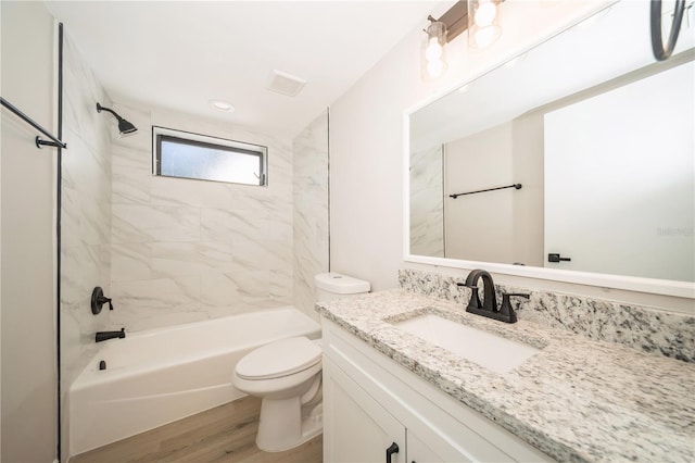 full bathroom featuring vanity, hardwood / wood-style floors, tiled shower / bath combo, and toilet