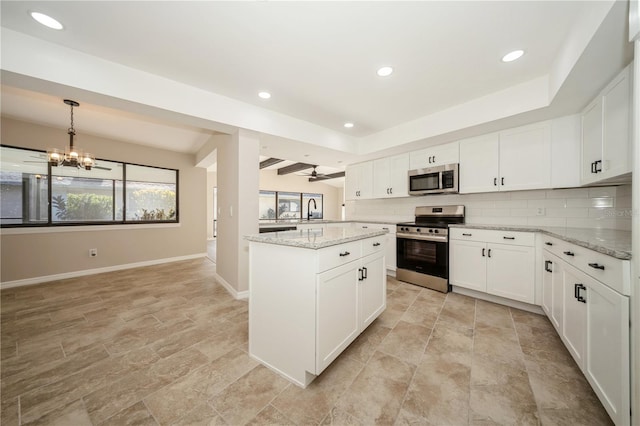 kitchen with backsplash, white cabinetry, stainless steel appliances, and light stone counters