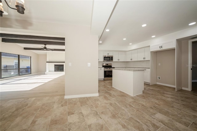 kitchen featuring ceiling fan with notable chandelier, stainless steel appliances, beamed ceiling, white cabinets, and a center island