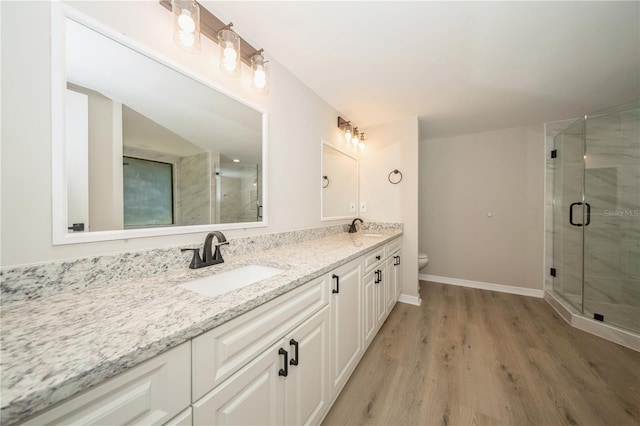 bathroom with hardwood / wood-style floors, vanity, an enclosed shower, and toilet