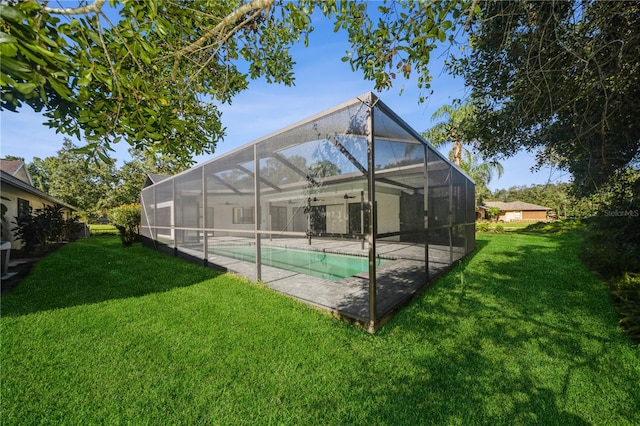 rear view of house featuring a lawn and glass enclosure