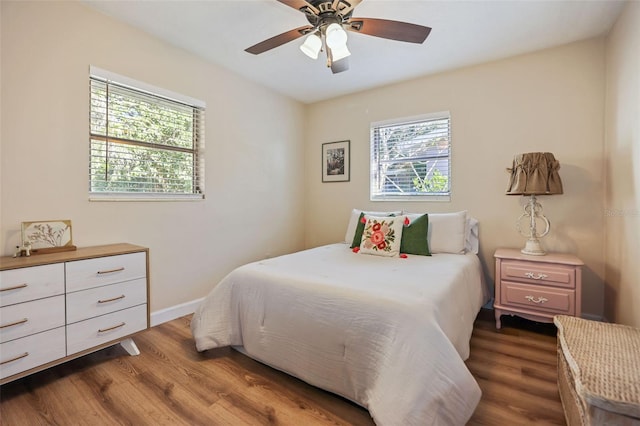 bedroom with ceiling fan, multiple windows, and hardwood / wood-style flooring