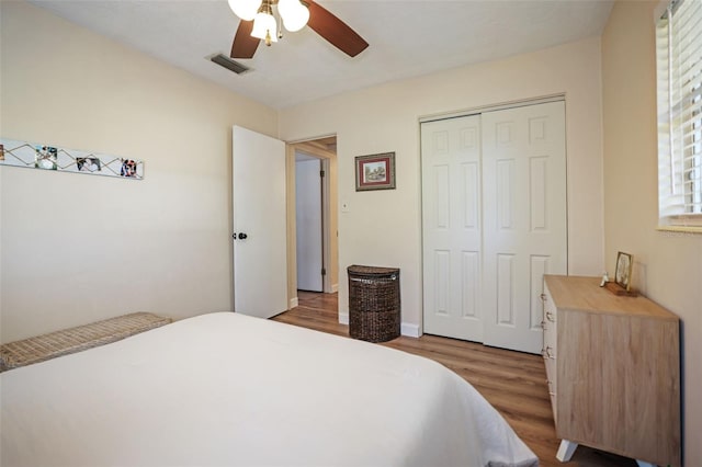 bedroom featuring ceiling fan, a closet, multiple windows, and hardwood / wood-style flooring