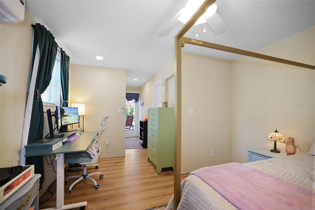 bedroom featuring ceiling fan, a wall unit AC, and light wood-type flooring