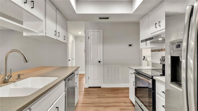 kitchen featuring sink, stainless steel appliances, white cabinets, exhaust hood, and light wood-type flooring