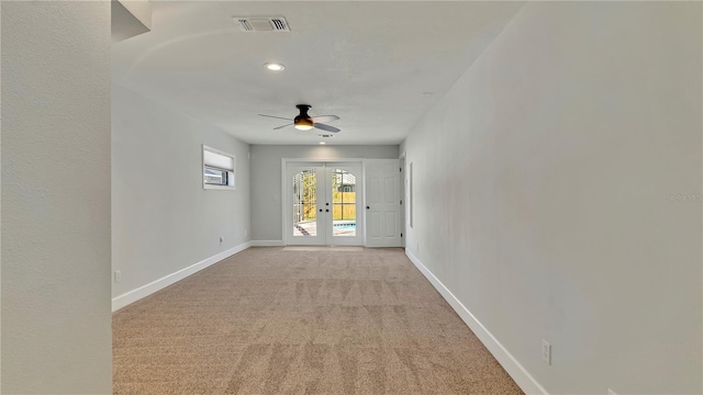 spare room featuring ceiling fan, french doors, and light carpet