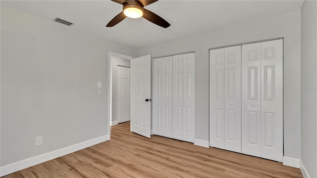 unfurnished bedroom with ceiling fan, light hardwood / wood-style flooring, and two closets