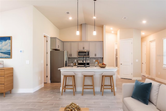 142 Fairway Rd, Rotonda West, FL 33947 - kitchen with appliances with stainless steel finishes, gray cabinetry, a kitchen breakfast bar, backsplash, and light countertops