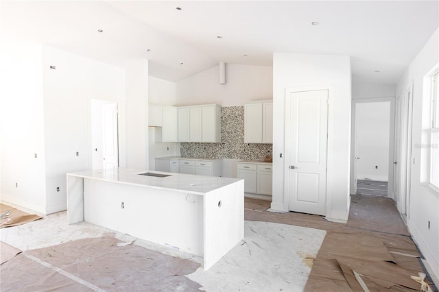 142 Fairway Rd, Rotonda West, FL 33947 - kitchen featuring vaulted ceiling, white cabinetry, a center island, and backsplash