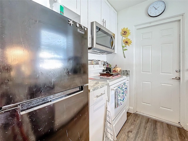 kitchen featuring light stone counters, white range with electric stovetop, black refrigerator, white cabinets, and light wood-type flooring