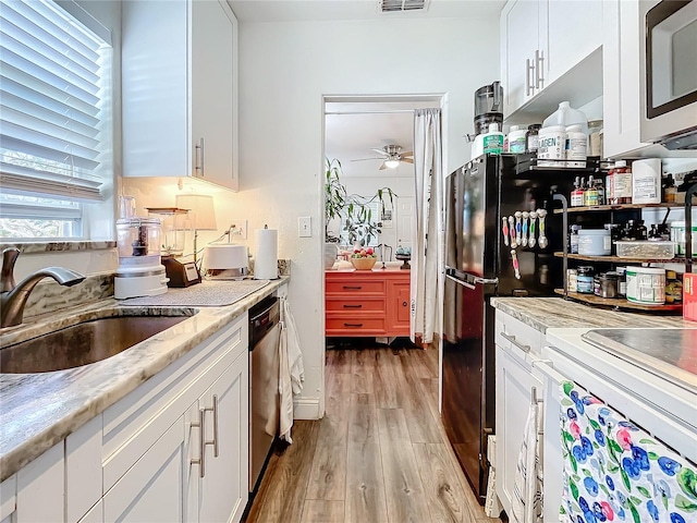 kitchen featuring sink, ceiling fan, light hardwood / wood-style floors, white cabinetry, and stainless steel appliances