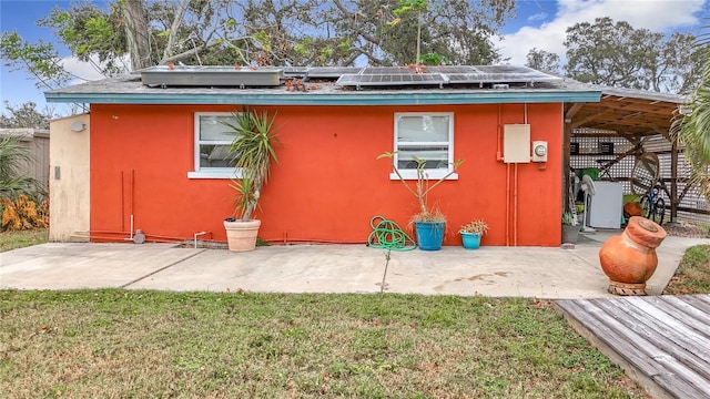 exterior space with a lawn, solar panels, and a patio