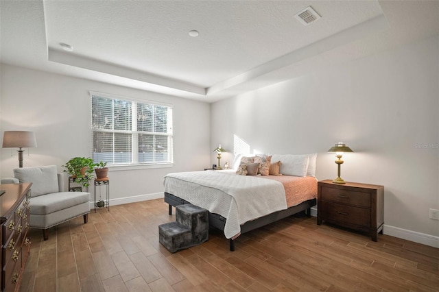 bedroom featuring hardwood / wood-style flooring and a raised ceiling