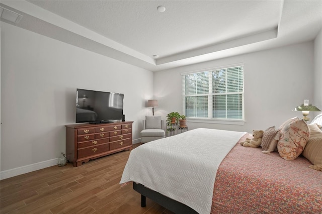 bedroom featuring hardwood / wood-style flooring and a raised ceiling