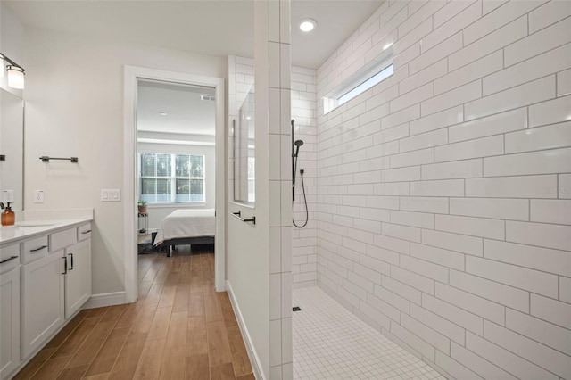 bathroom featuring tiled shower, hardwood / wood-style floors, and vanity