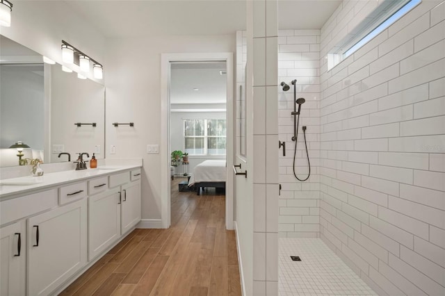 bathroom with hardwood / wood-style flooring, vanity, and a tile shower