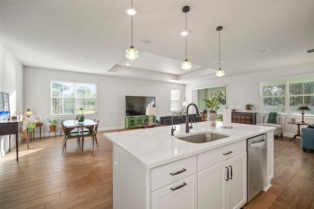 kitchen with pendant lighting, a kitchen island with sink, white cabinets, sink, and stainless steel dishwasher