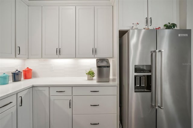 kitchen featuring decorative backsplash, high end fridge, and white cabinetry