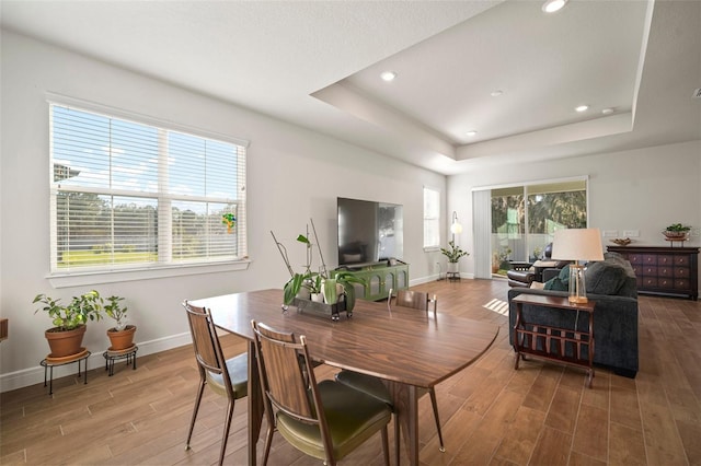 dining space with hardwood / wood-style flooring and a tray ceiling