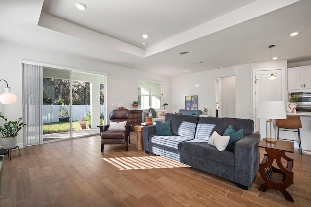 living room featuring hardwood / wood-style floors and a tray ceiling