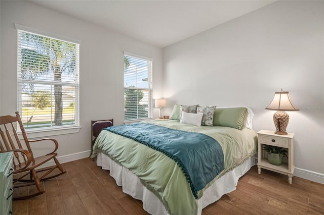 bedroom with multiple windows and dark hardwood / wood-style floors