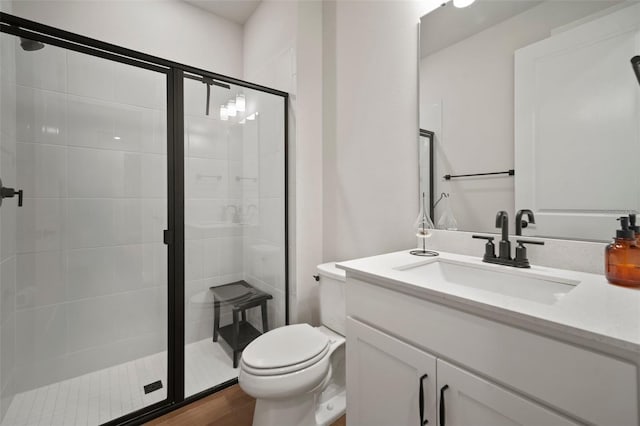 bathroom with vanity, hardwood / wood-style flooring, toilet, and an enclosed shower