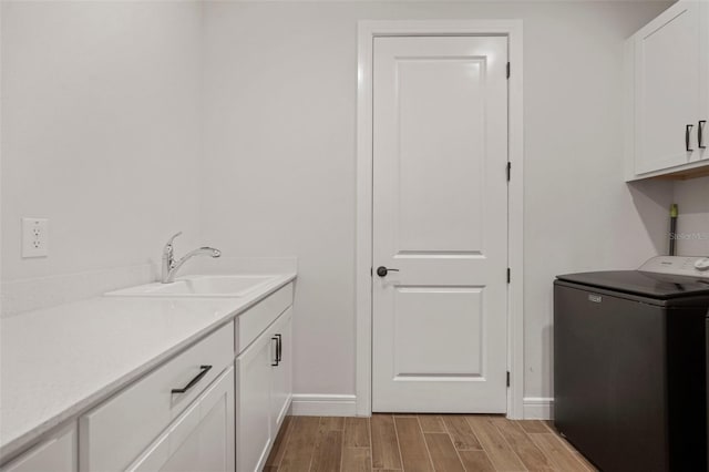 laundry area with cabinets, washer / clothes dryer, light hardwood / wood-style flooring, and sink