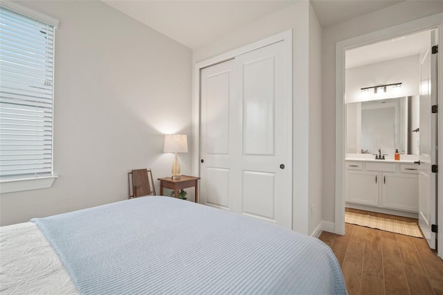 bedroom with hardwood / wood-style flooring, a closet, sink, and ensuite bath