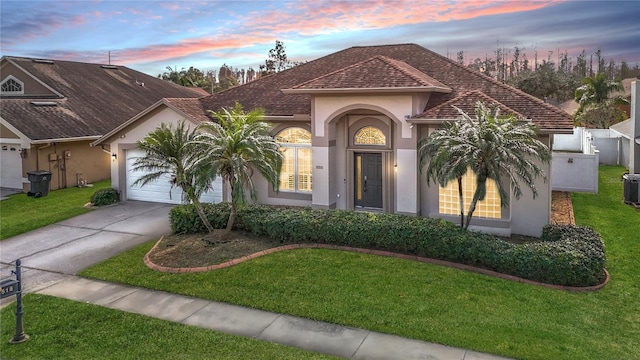 mediterranean / spanish-style home with a garage and a lawn