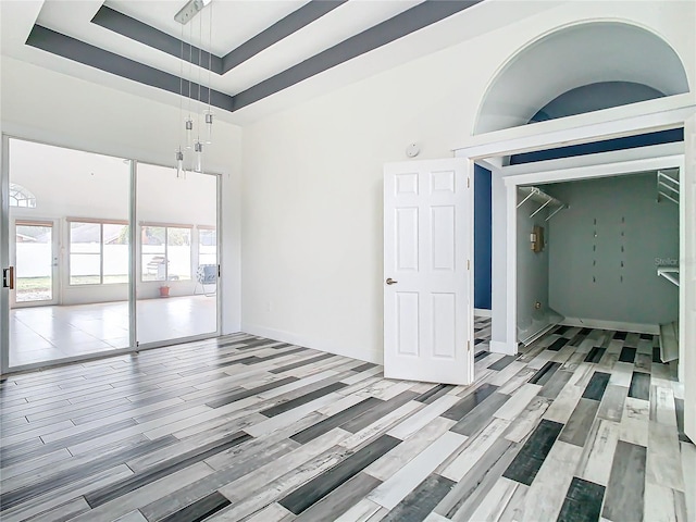 spare room with light hardwood / wood-style floors, a raised ceiling, and a high ceiling