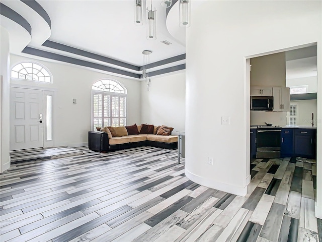 living room with sink, light hardwood / wood-style floors, and a raised ceiling