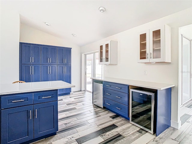 kitchen featuring lofted ceiling, beverage cooler, refrigerator, and blue cabinets