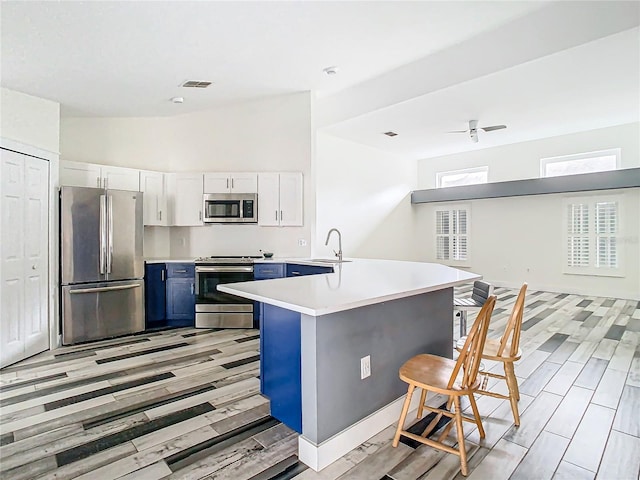 kitchen featuring blue cabinets, a breakfast bar, sink, white cabinetry, and stainless steel appliances