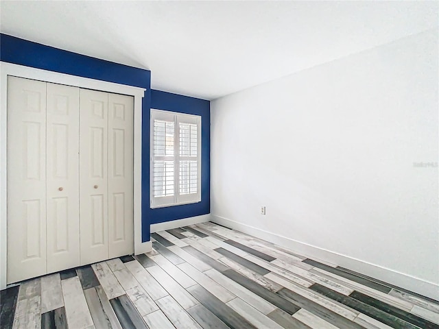 unfurnished bedroom with light hardwood / wood-style flooring and a closet